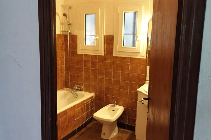 Bath, bidet and sink unit in a bathroom with light brown tiles
