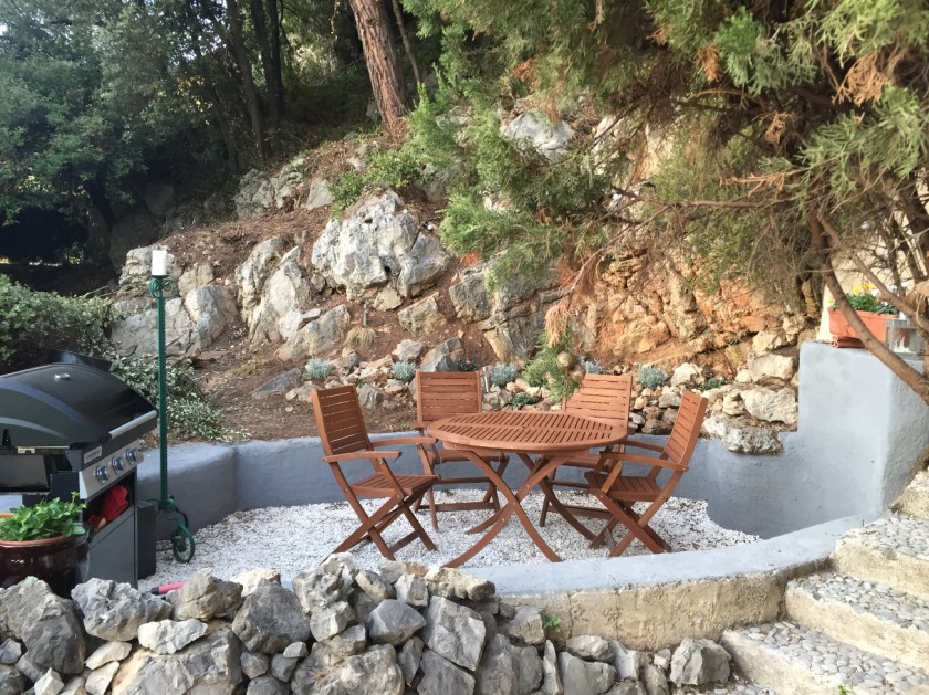 Patio with table and chairs surrounded by forest and rocks