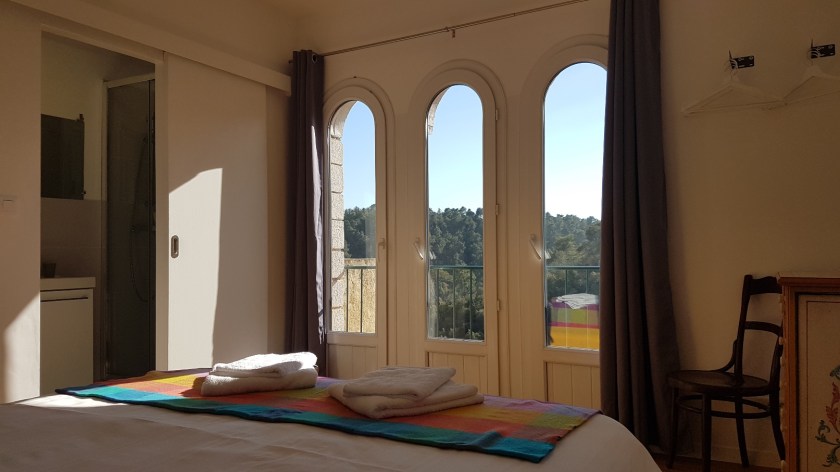 Bedroom with double bed and three glass doors looking out on the forest